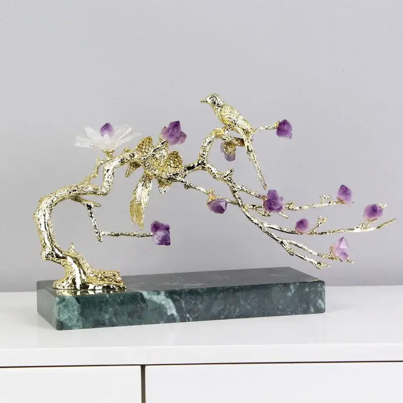 Artisan amethyst and golden tree handicraft featuring a golden tree adorned with purple crystals and white flower on marble base