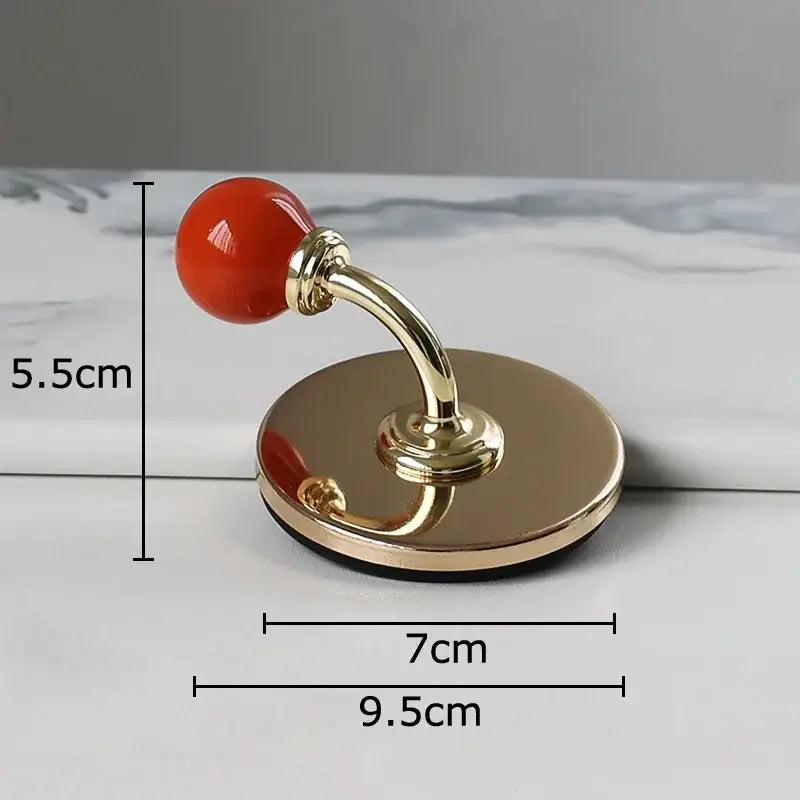 A polished gold-toned doorstop with a glossy red spherical knob and reflective base for decorbites colorful wall hooks storage organizer