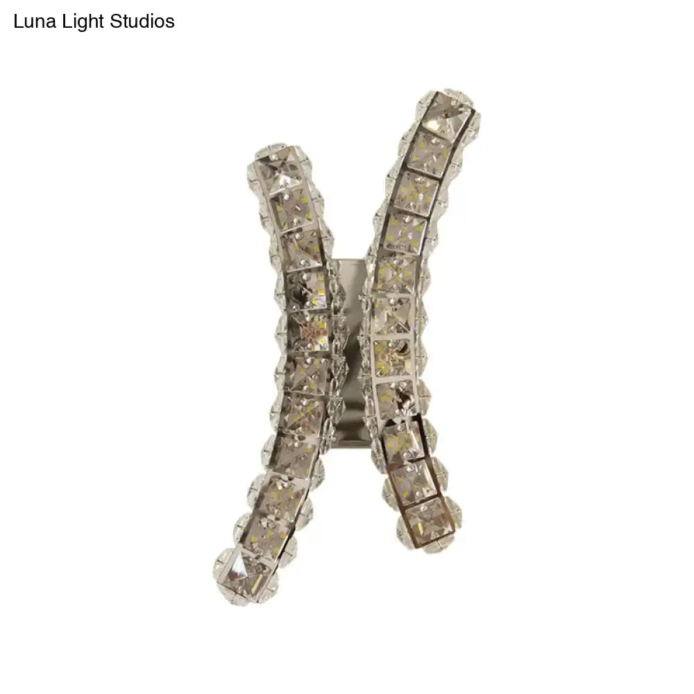 A sparkling silver h-shaped hair clip with clear faceted crystals matching chrome curvy crystal prism wall sconce design