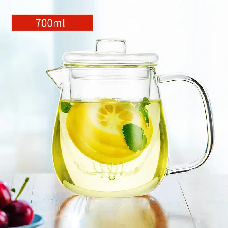 Clear glass floral tea cup with filter and lid filled with lemon-infused green tea and fresh mint leaves