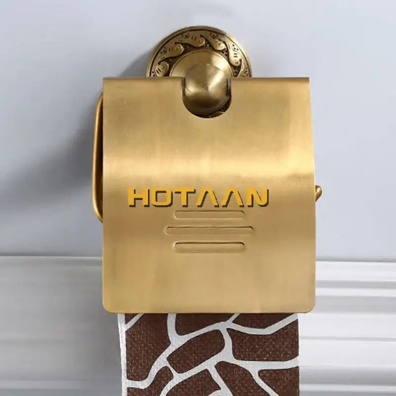 Gold-colored brass toilet paper holder with ornate circular mount and embossed hotaaan branding for vintage bathroom use