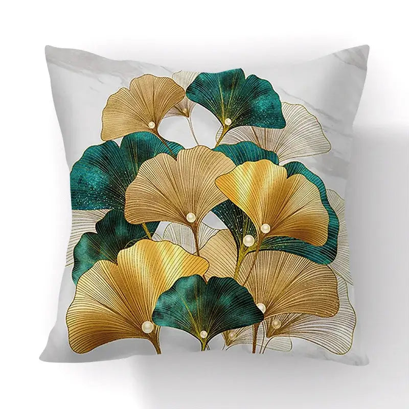 Square throw pillow with decorbites ginkgo leaves print in gold and teal on white marble background for sofa use