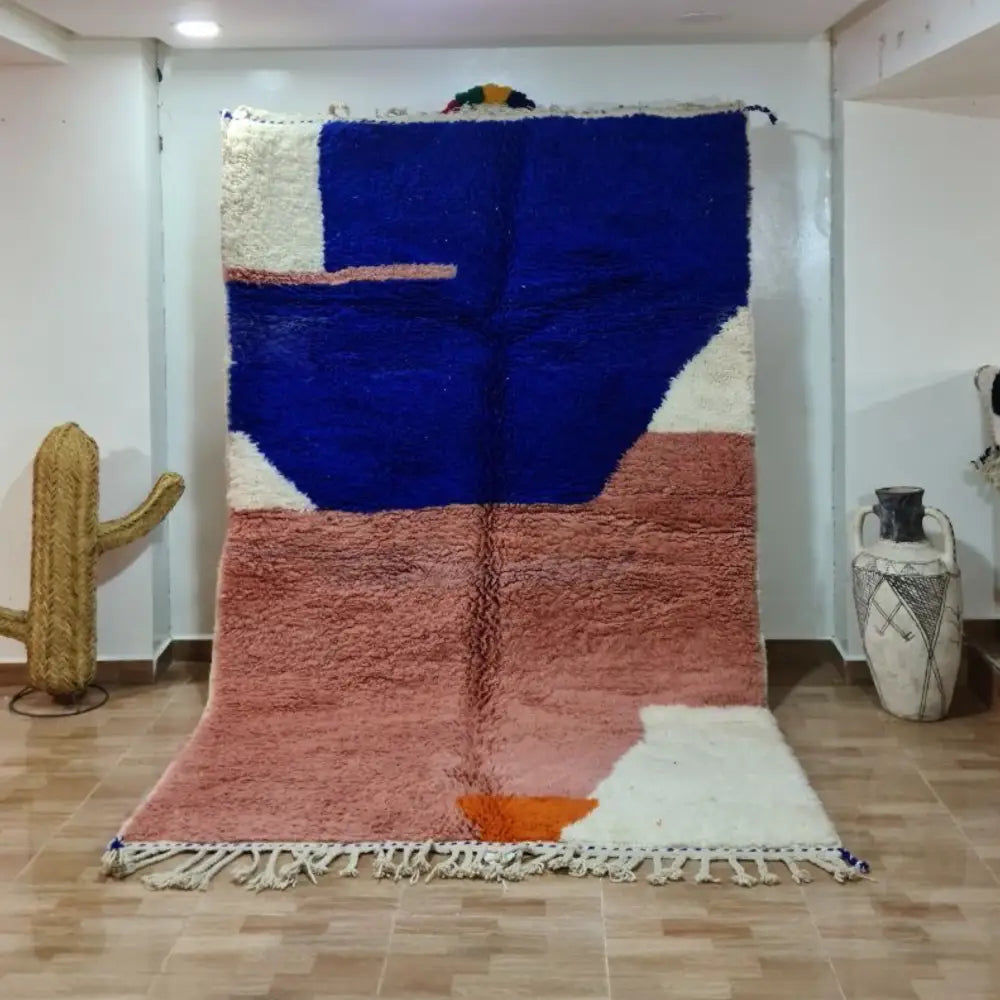 A plush geometric beni ouarain moroccan handmade carpet in bold blue pink and cream with fringed edges by DecorBites