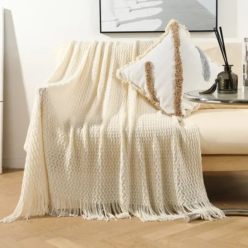 Cream-colored geometric knit sofa blanket with textured knit and fringe tassel detail by decorbites for living room decor