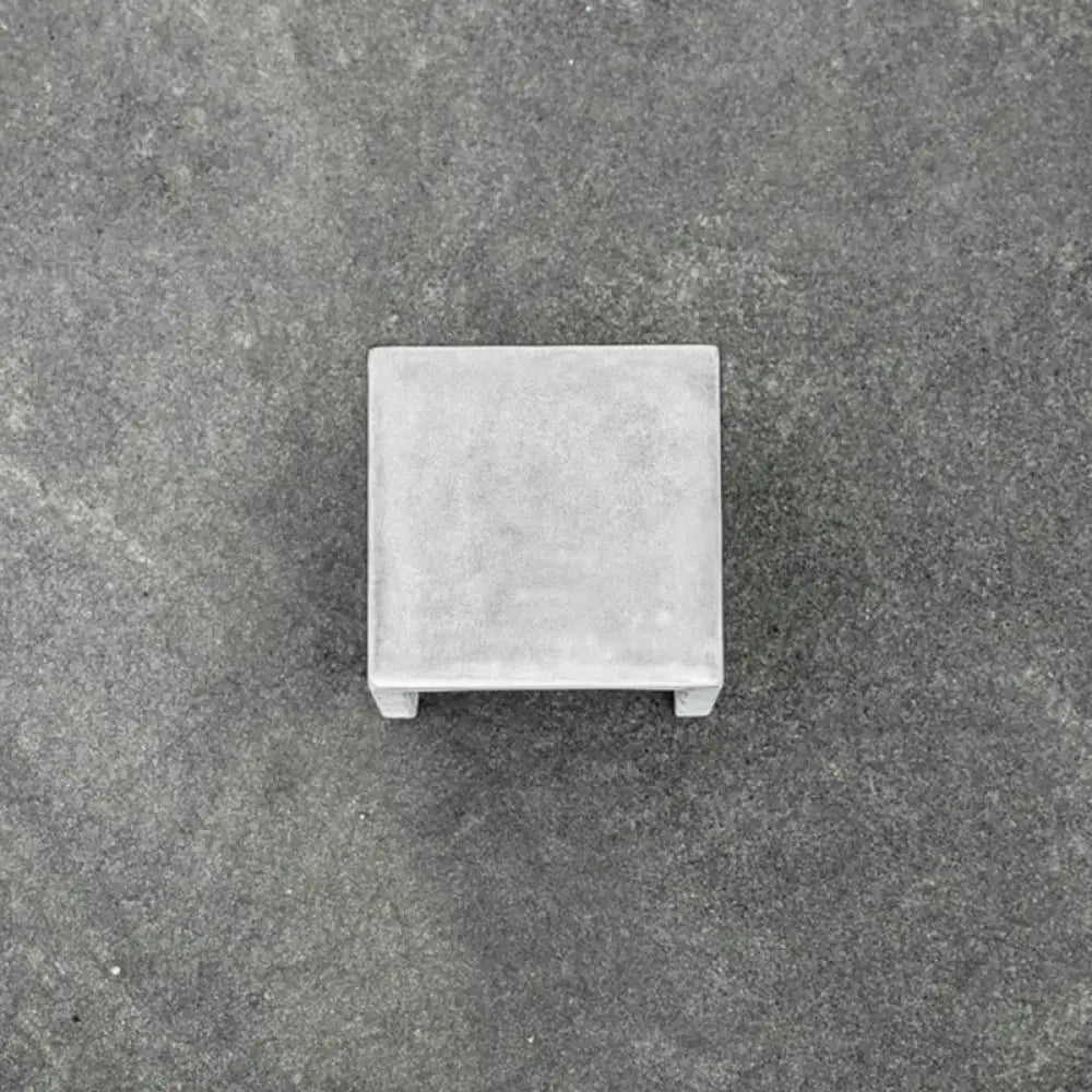 Gray concrete square pedestal with textured surface and small feet for minimalist black cement led wall lamp use
