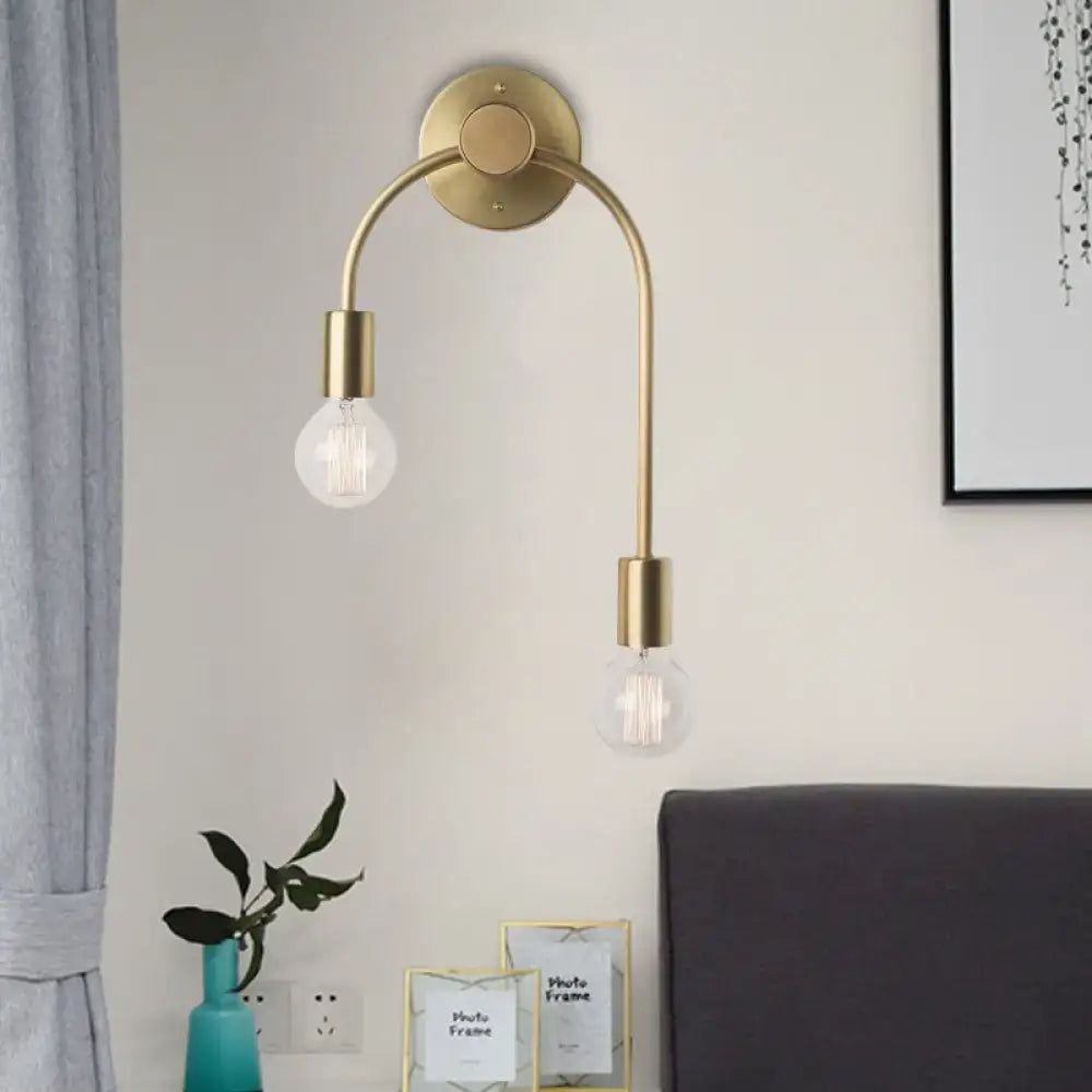 Brass-toned minimalist black and gold wall lamp with two curved arms and exposed filament bulbs for bedroom use