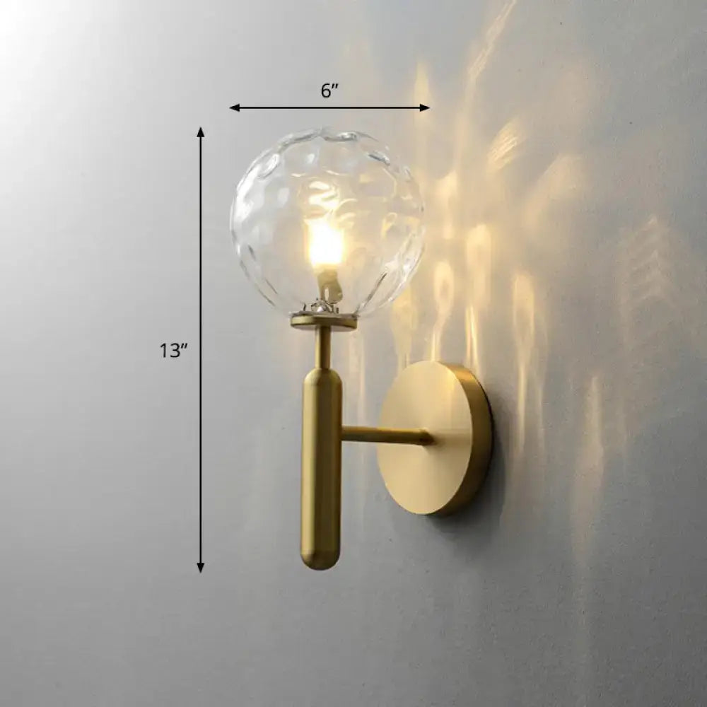 Minimalist brass wall sconce with cream glass shade and textured clear glass globe for living room lighting