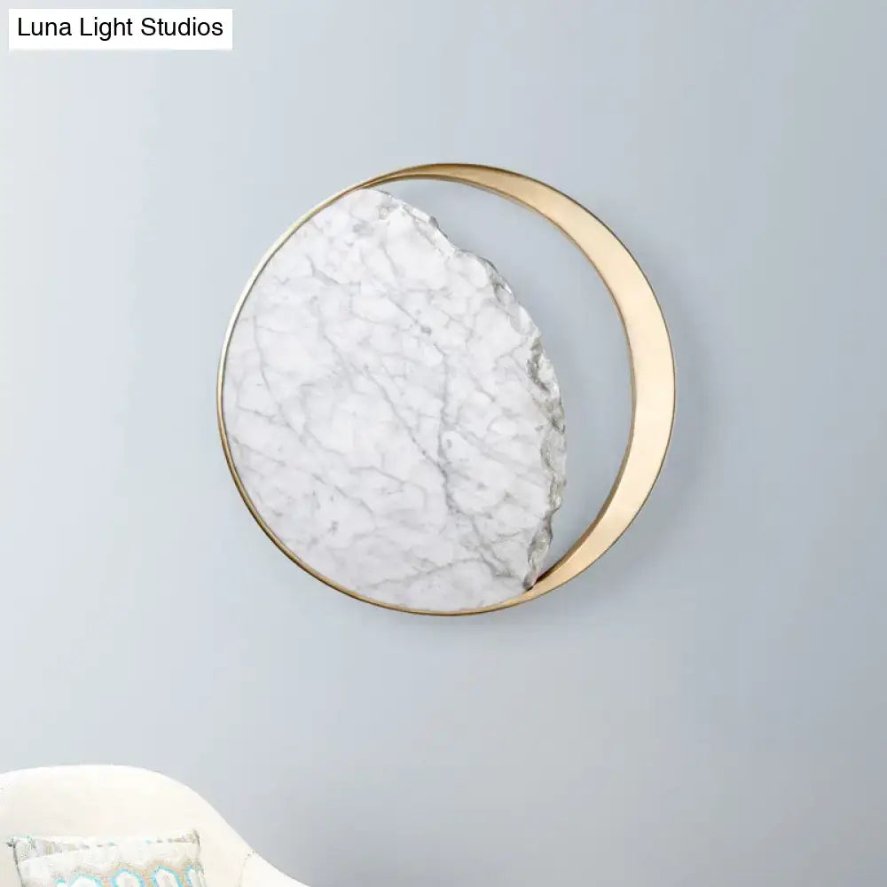 Minimalist gold and white moon wall lamp with white marble and gray veining framed by gold metal crescent for living room