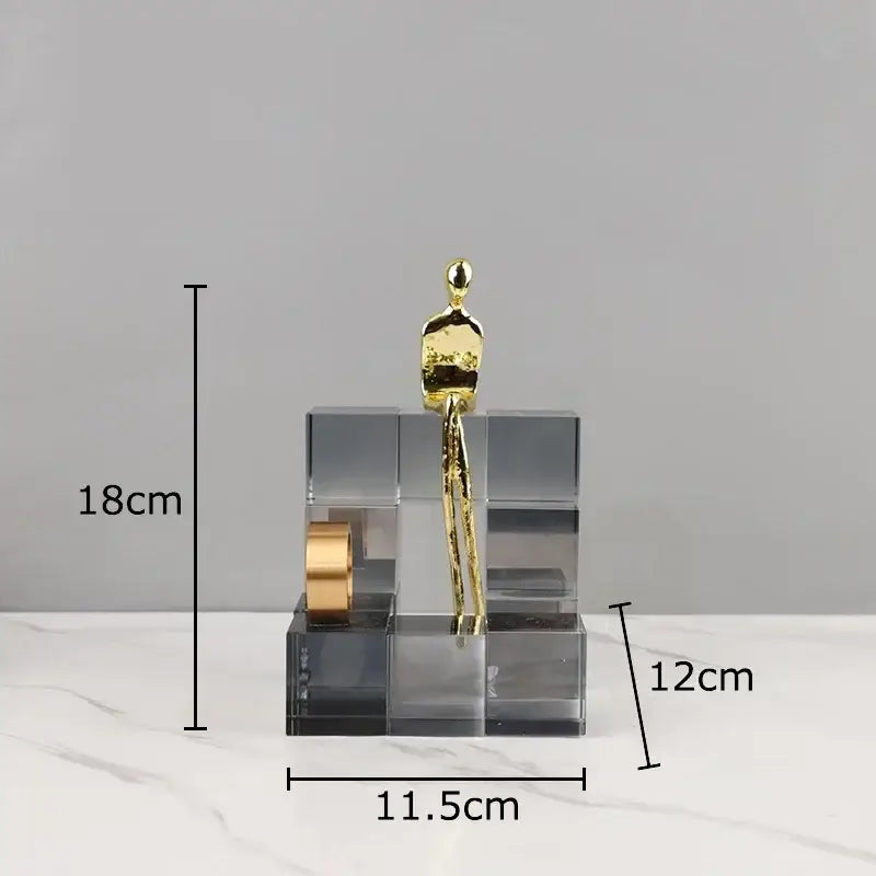 Gold-colored abstract decorbites golden thinker perched on a transparent thinker crystal base with geometric cube design