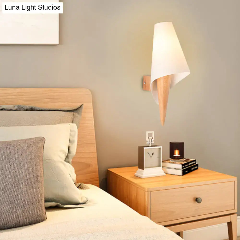 A minimalist wall-mounted light fixture with a white fabric shade and light wood base for bedroom use
