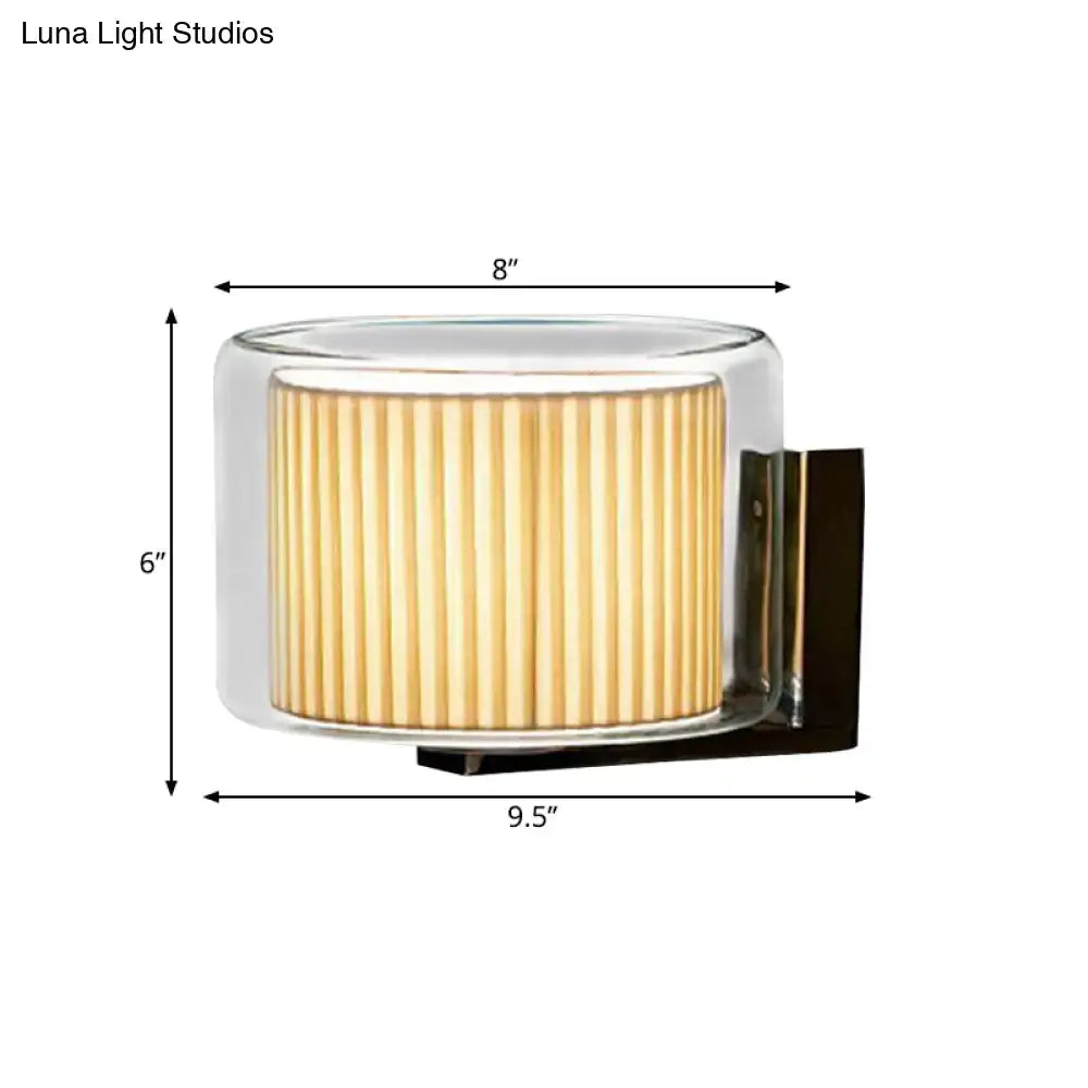 Modern amber and black wall lamp with pleated fabric shade, clear glass casing, and black metal mounting bracket