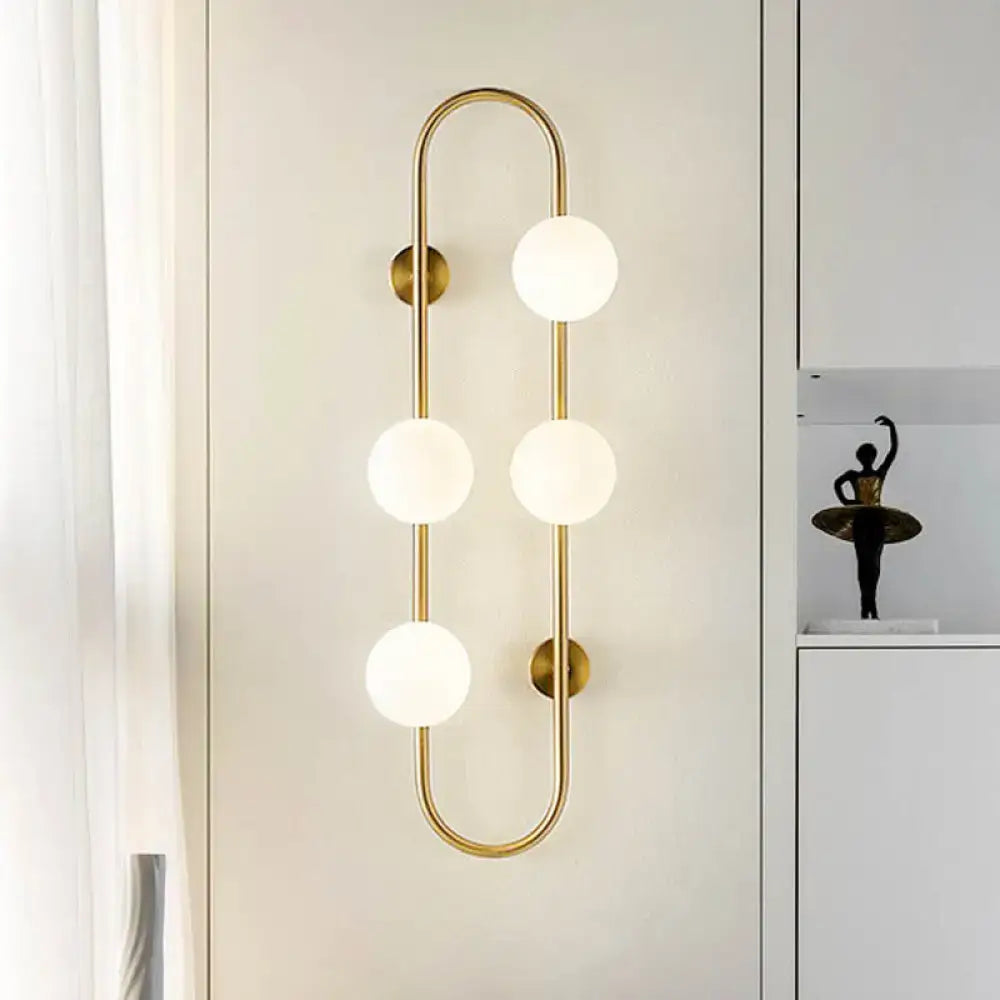 Modern black and gold globe wall sconce with four white glass frosted bulbs in a curved design for bedroom lighting