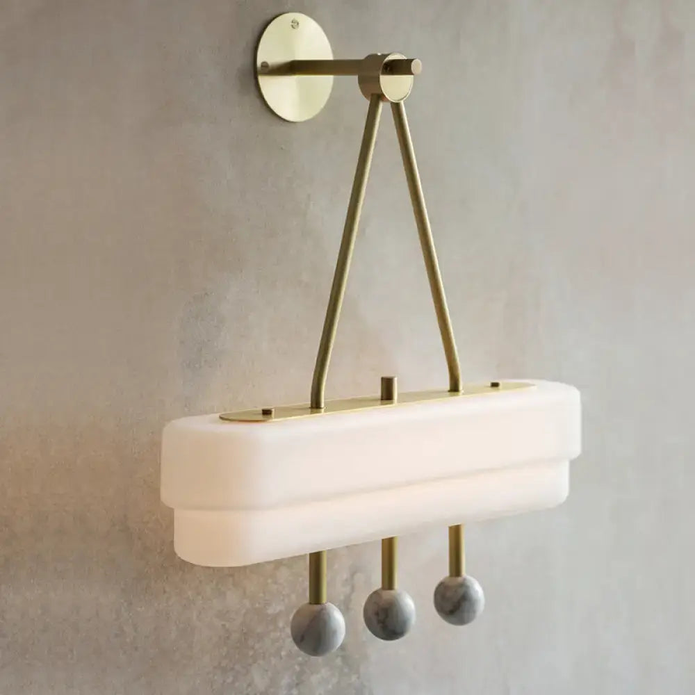 Modern brass and gray sconce light fixture with matte white glass shade and marble spheres as dining room wall lamp