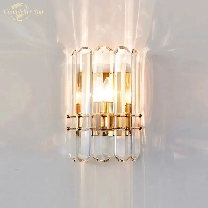 Elegant gold-toned modern geometric nordic wall sconce with faceted crystal columns refracting light beautifully