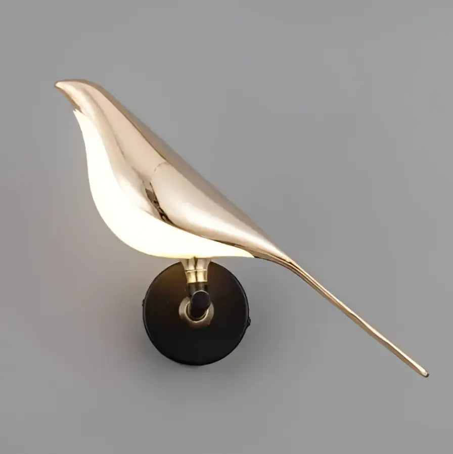A sleek gold-toned bird-shaped led wall lamp with polished metallic finish and black circular base for modern decor