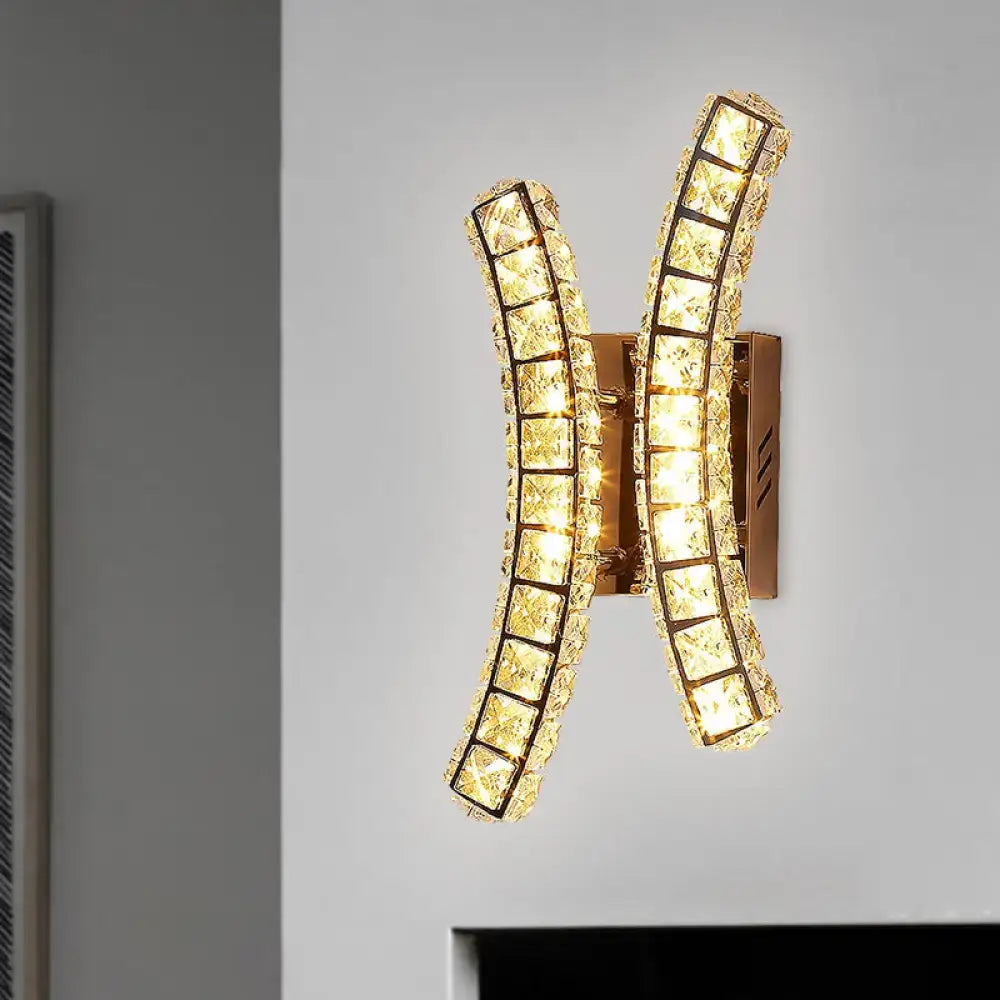 Modern gold crystal dual wall sconce with two curved crystal dual vertical arms emitting warm and white light for bedroom use