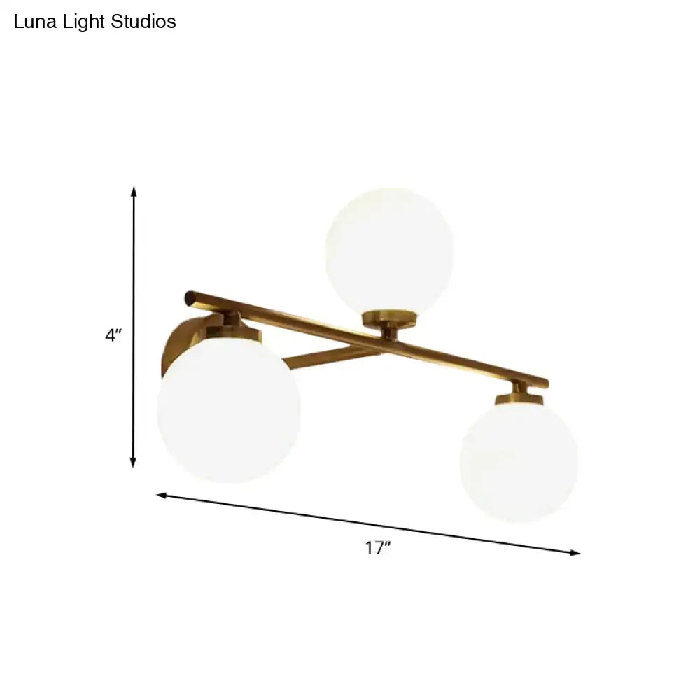 Modern wall lamp with brass finish and three frosted globe opal glass shades for bedroom sconce lighting