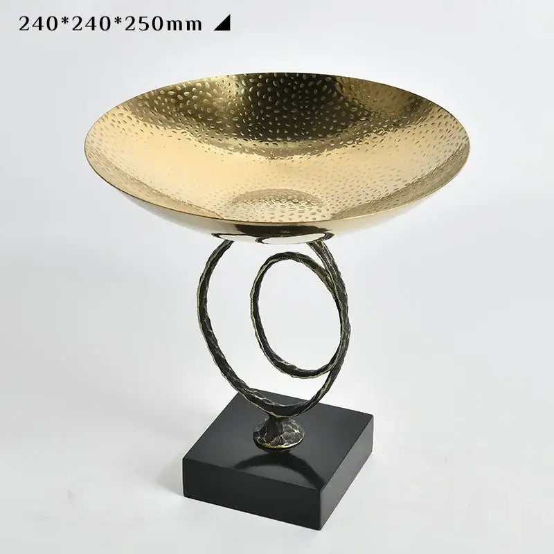 Modern gold hammered fruit bowl tray with a sculptural black metal base and intertwined ring stand for dining room use