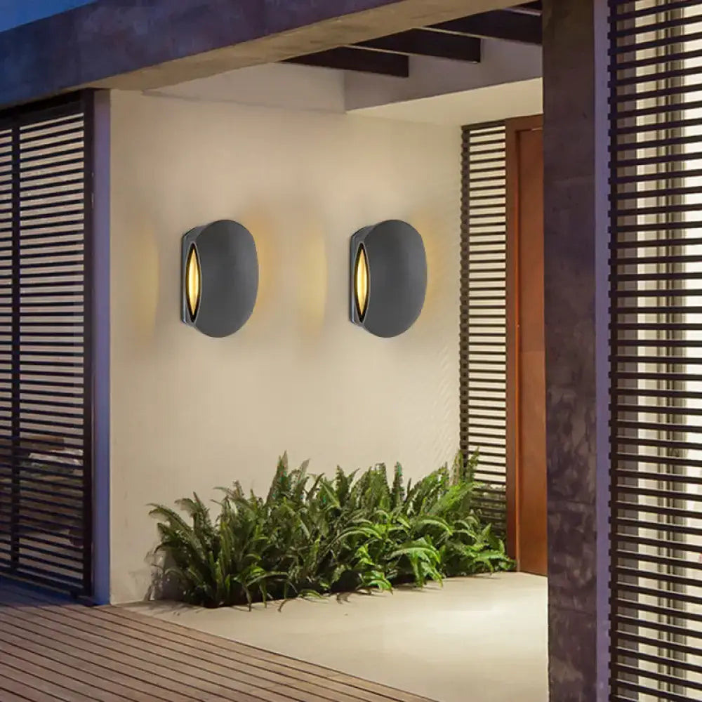 Modern gray oval wall light with warm white bulb included emitting light from central vertical slit for outdoor use
