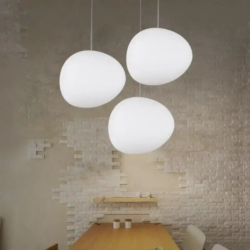 Three white egg-shaped modern matte glass pendant lights hanging from the ceiling for living room lighting