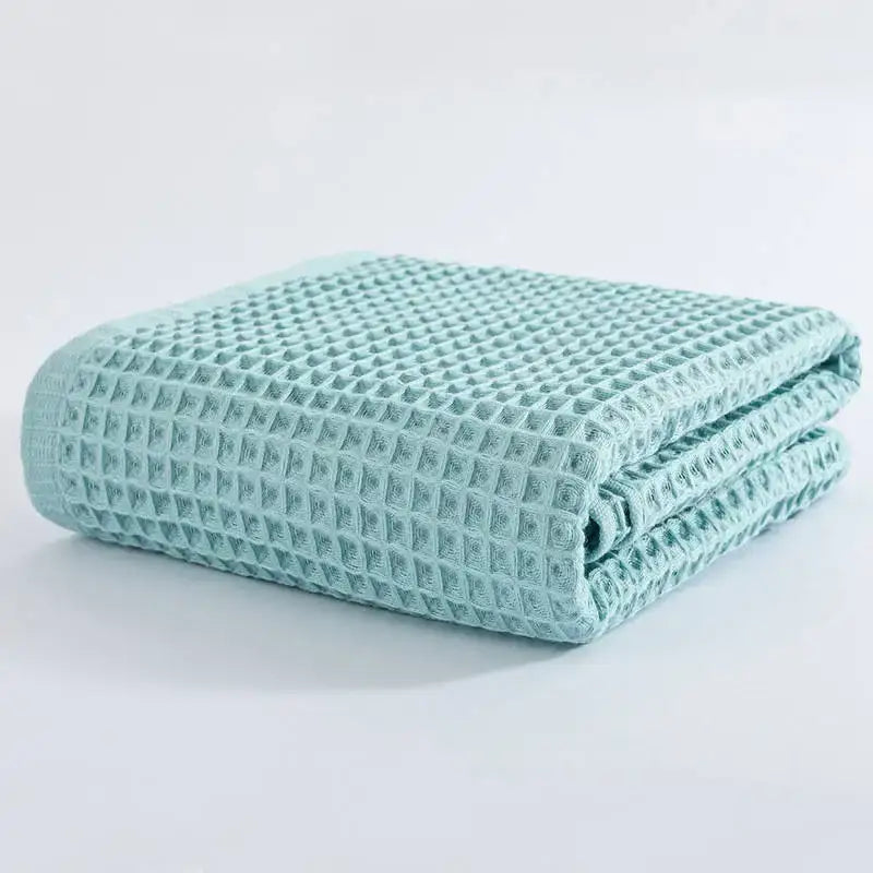 A neatly folded mint green cotton waffle bath towel with a textured grid pattern from decorbites cotton waffle set