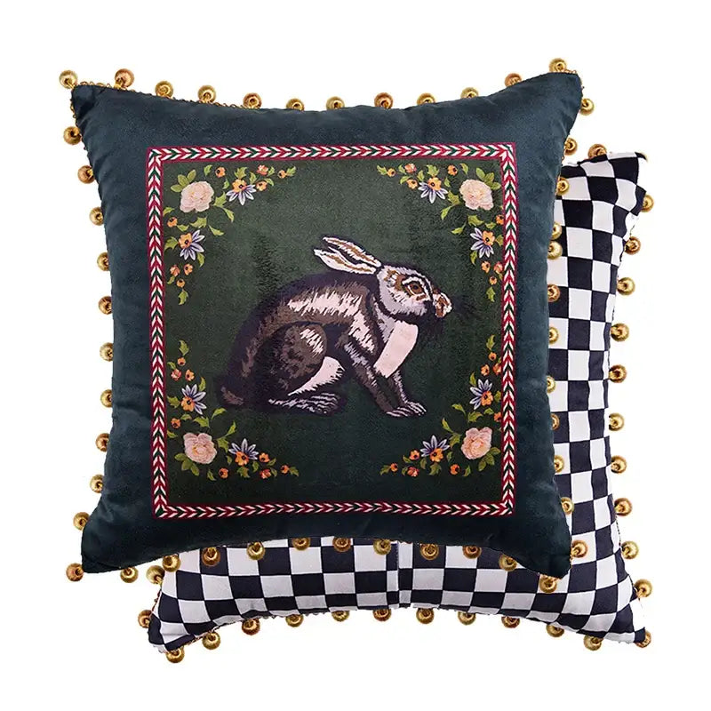 Dark green velvet throw pillow with embroidered rabbit floral motifs and gold pom-poms complementing decorbites cat print velvet designs