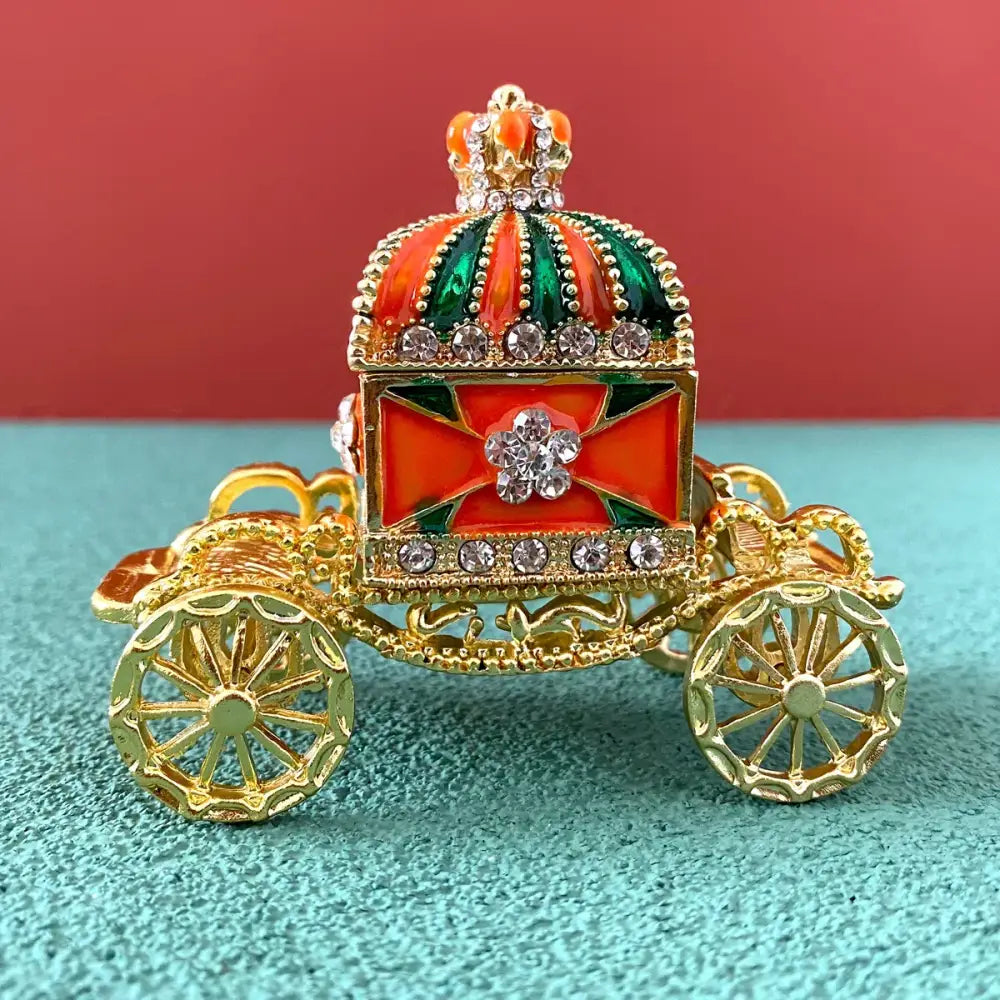 Decorative gold carriage jewelry trinket box with red and green enamel rhinestones and a jeweled crown topper
