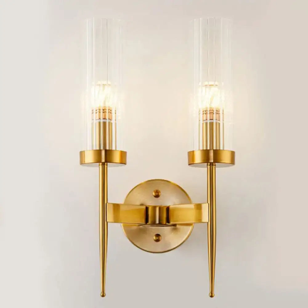 Postmodern gold-toned wall sconce with two clear ribbed glass cylinders housing illuminated bulbs for stairway lighting