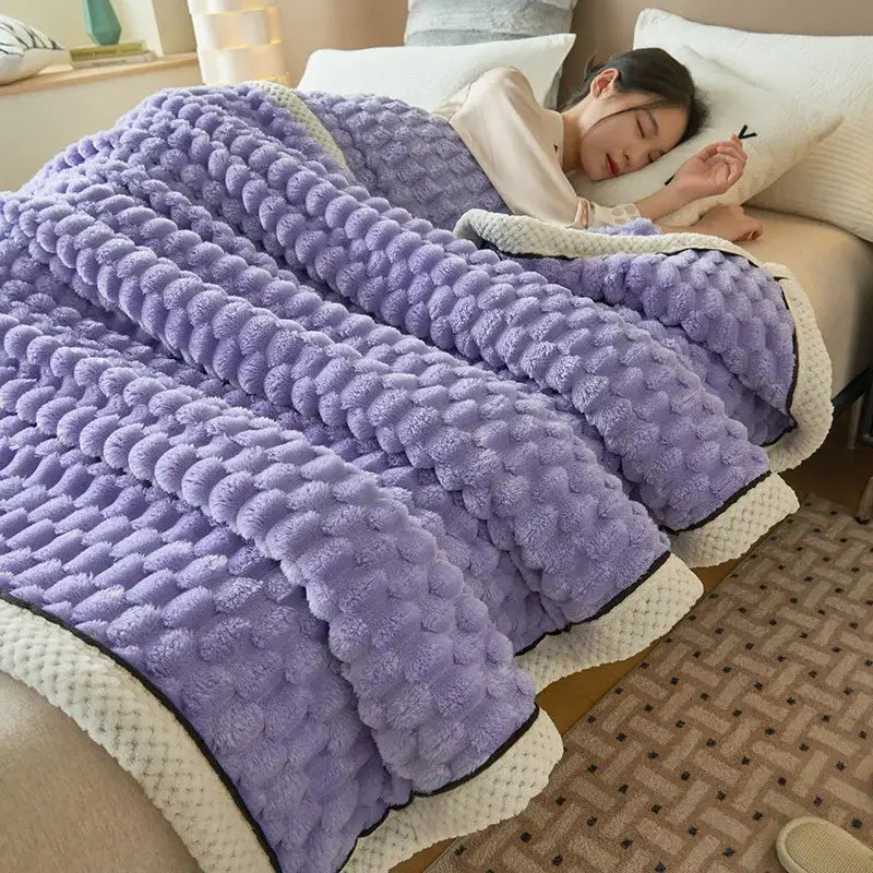 A plush lavender coral fleece warm blanket with textured raised dots and cream-colored border trim by decorbites