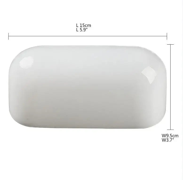 A sleek white ceramic soap dish with rounded edges shown alongside a traditional emerald green decorbites glass bankers lamp cover