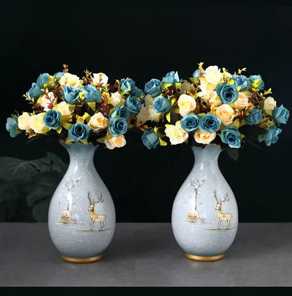 Pair of light blue ceramic vases with gold-trimmed bases and deer illustrations holding dried flowers bouquets
