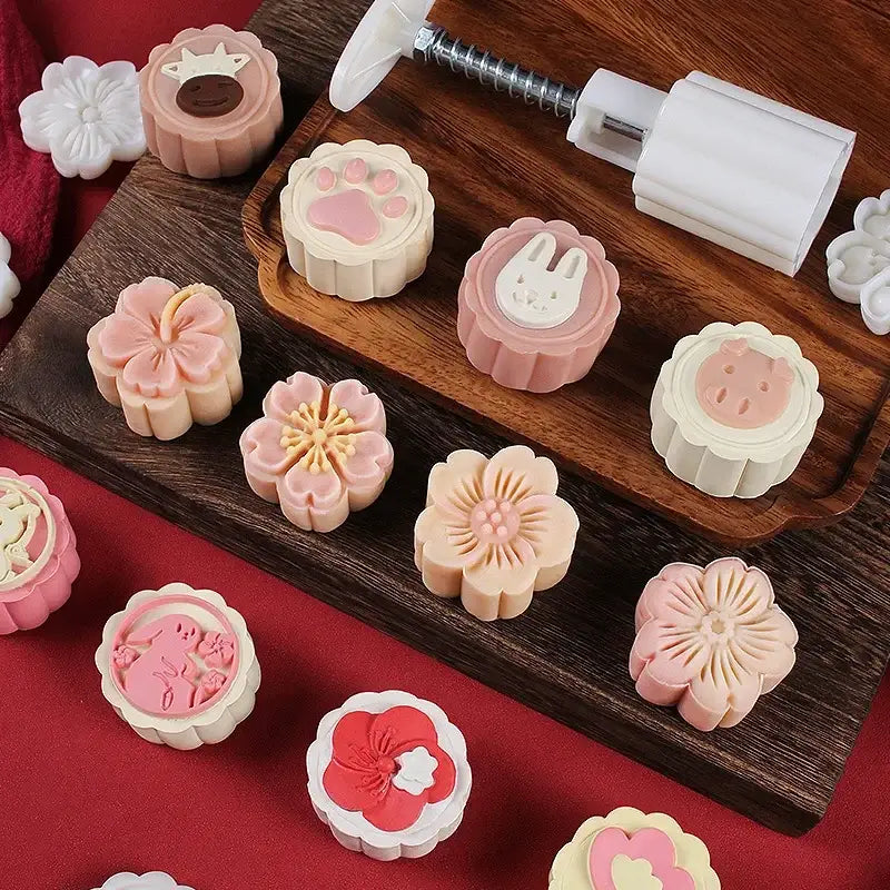 Pastel pink and cream 3d cherry blossom mooncake molds with floral animal and heart designs on wooden tray for baking