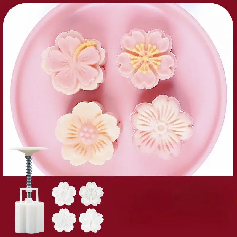 Pink and cream-colored plastic cherry blossom mooncake molds with intricate petal designs and white pressing tool for baking