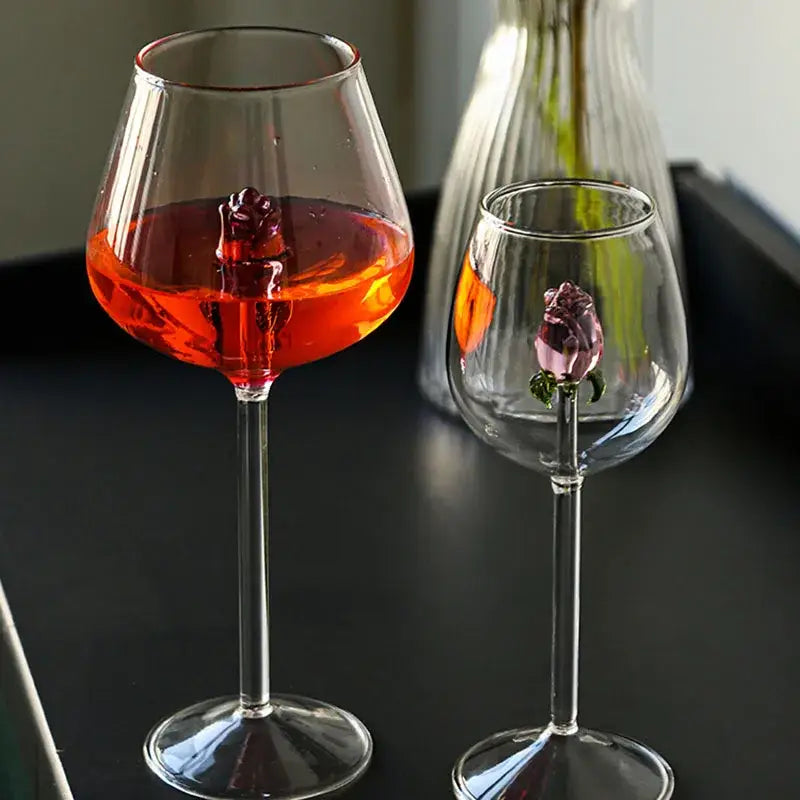 Clear glass rose wine goblets with 3d pink glass rose embellishments one filled with vibrant red liquid decorbites 3d pink