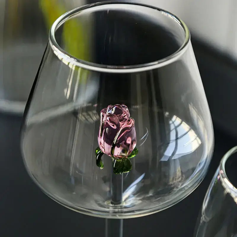 A delicately crafted decorbites 3d pink glass rose with green leaves inside a clear glass rose wine goblet