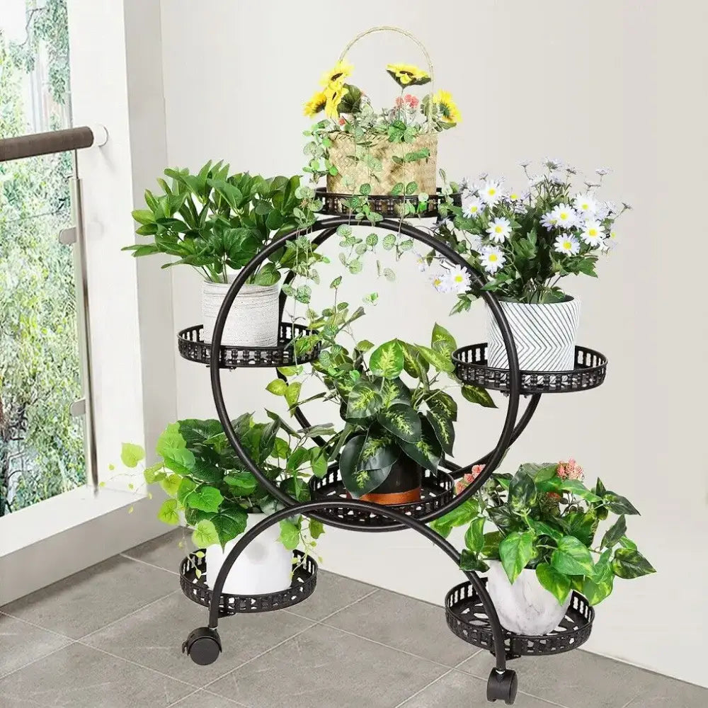 Black wrought iron decorbites plant stand shelf with decorative perforated tiers and caster wheels holding six pots