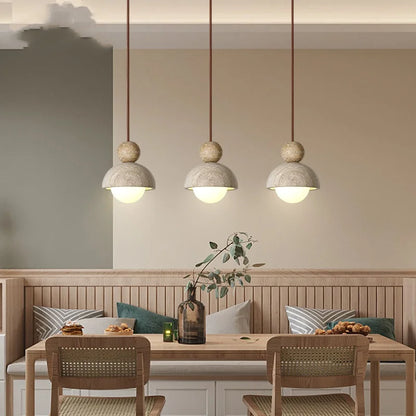 Three decorbites led pendant lights with matte concrete shades and warm cords hang above a wooden dining table
