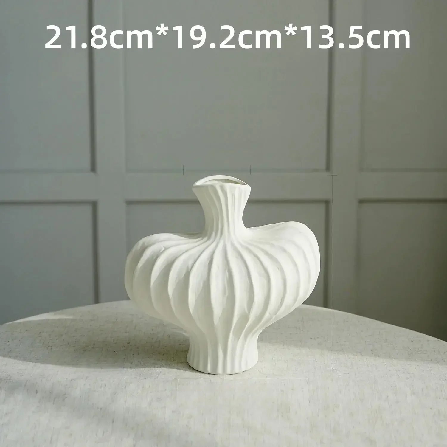 A white ceramic ribbed vase with flared neck from a hollow plastic imitation vase set for modern decor made in mainland China