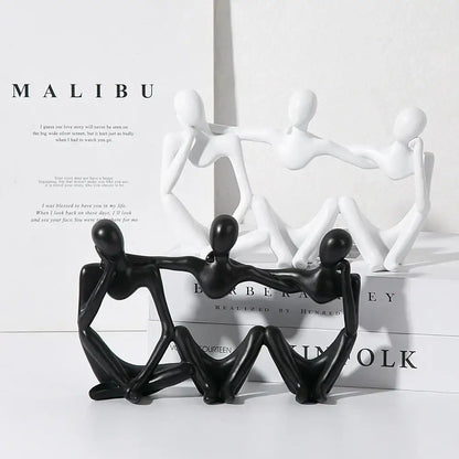 Black glossy abstract friendship figurine of three interconnected human figures in a seated pose for living room decor