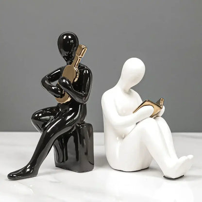 Black glossy ceramic character bookends in abstract nordic style featuring seated person playing guitar with gold accents