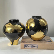 Two glossy black ceramic vases with abstract gold foil pattern in rounded and bulbous shapes for living room decor