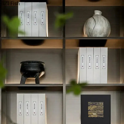 A sleek modern bookshelf with warm wood accents next to a black and gold gilded fabric hanging painting decorbites
