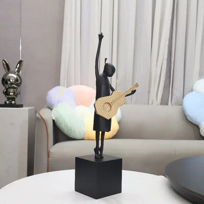 Abstract black and gold guitarist resin sculpture featuring a black resin dancer holding a woven gold guitar on a black cube base