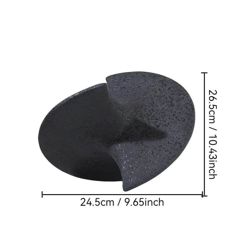 Black textured stone foot file with smooth curved surface and cutout alongside geometric ceramic gyroscope ornaments
