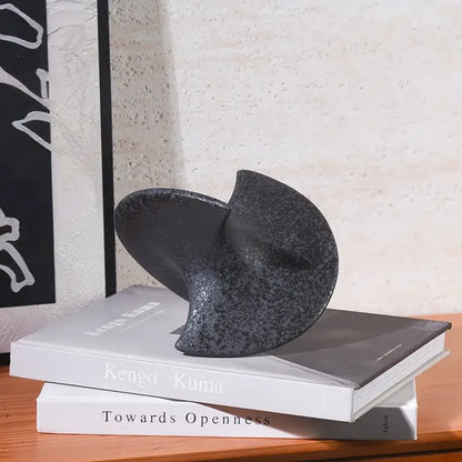 Dark gray speckled ceramic bookend with smooth sculpted spiral design as geometric ceramic gyroscope ornament