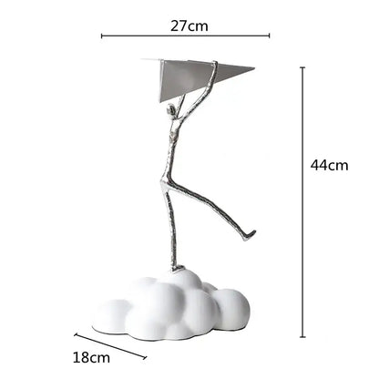 Silver metallic figurine holding a triangular resin paper airplane on a white cloud base for living room decor