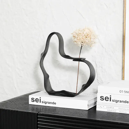 Abstract black resin ring sculpture with metal vase holding dried white hydrangea for decorbites home decor