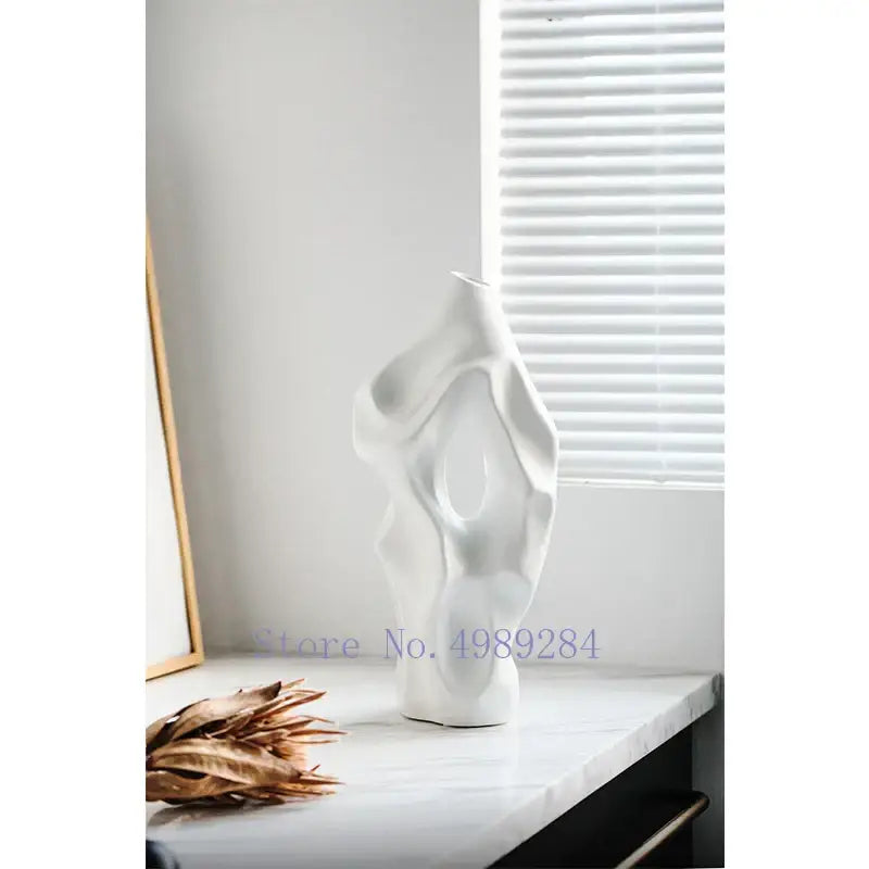 White abstract ceramic vase with organic flowing contours and central hollow opening decorbites black living room decor