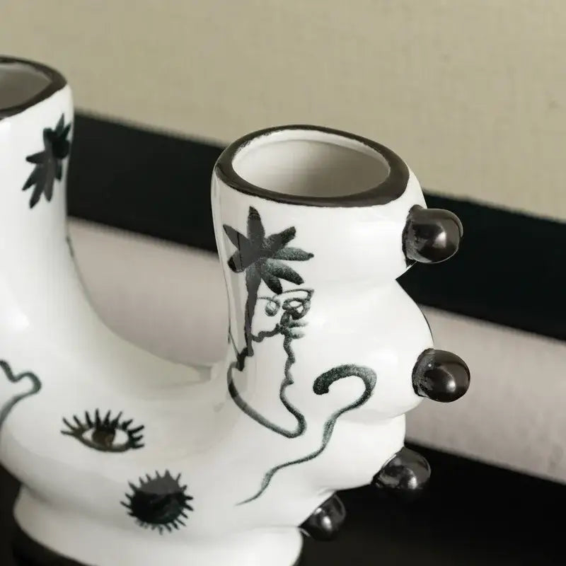 White ceramic boot-shaped graffiti ceramic vase with black hand-painted illustrations and glossy black accents for decorbites decorbites graffiti