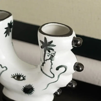 White ceramic boot-shaped graffiti ceramic vase with black hand-painted illustrations and glossy black accents for decorbites decorbites graffiti